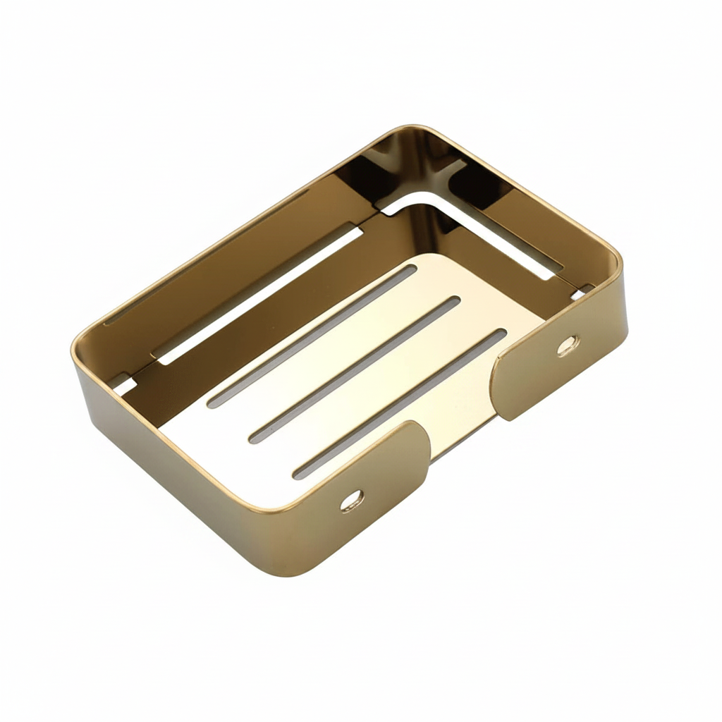 Gold-colored stainless steel soap dish with a rectangular shape, featuring a slotted bottom and a small loop on one side, shown on a reflective white surface.

