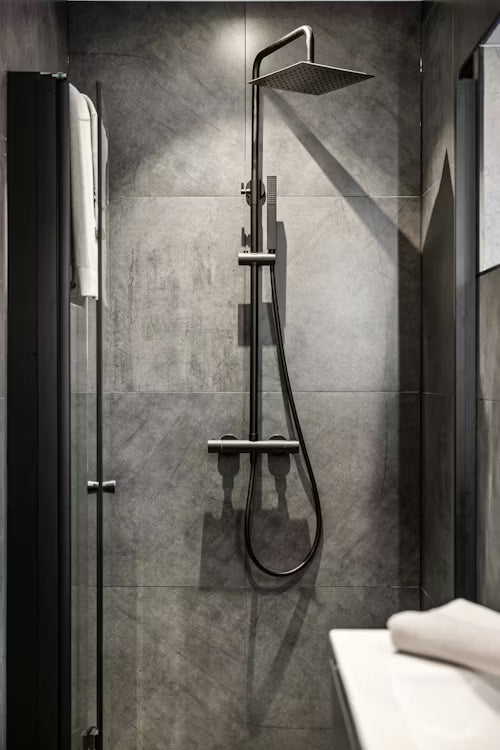 Modern shower setup with a rain shower head and handheld shower on a tiled wall.